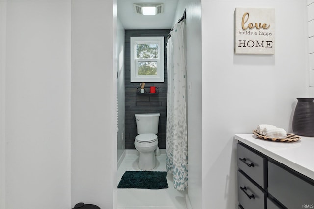 bathroom with tile walls, vanity, toilet, and tile patterned floors