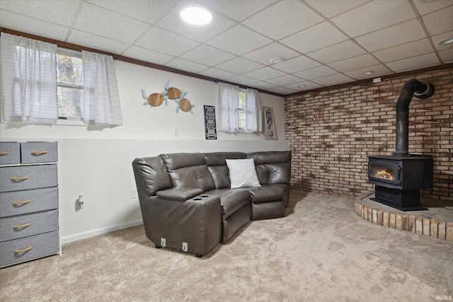 living room with a paneled ceiling, a wood stove, plenty of natural light, and light colored carpet