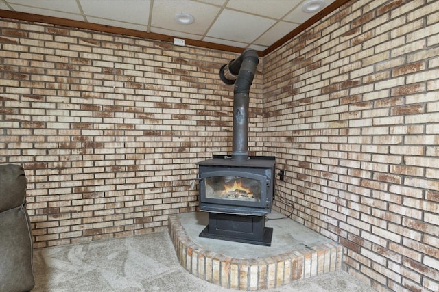 interior details featuring a drop ceiling, carpet floors, and a wood stove