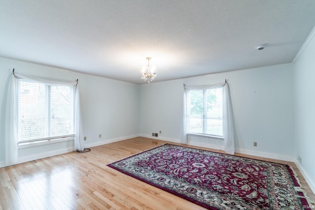 unfurnished room featuring crown molding, a healthy amount of sunlight, a chandelier, and hardwood / wood-style floors