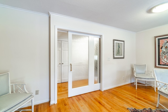 sitting room featuring crown molding, wood-type flooring, and a textured ceiling