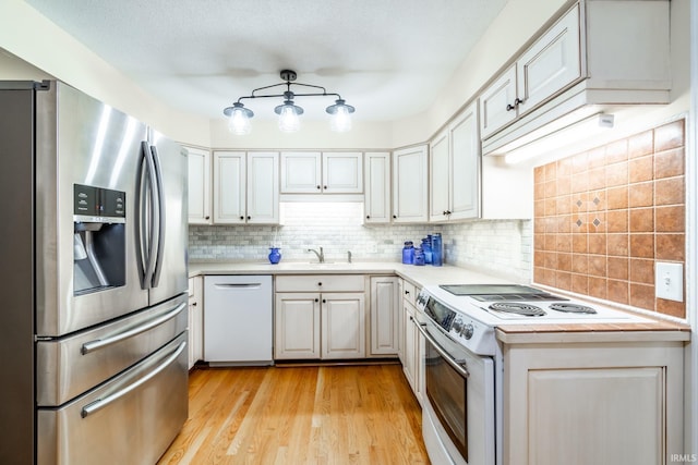 kitchen with light hardwood / wood-style floors, backsplash, sink, white cabinetry, and white appliances