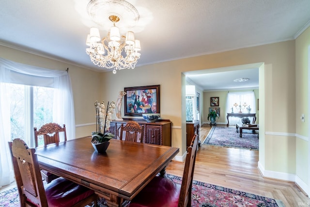 dining room with ornamental molding, a chandelier, and light hardwood / wood-style floors