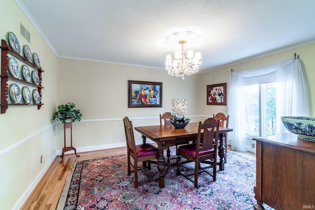 dining area with ornamental molding, a notable chandelier, and light hardwood / wood-style floors