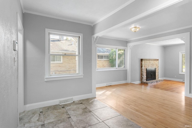 unfurnished living room featuring ornamental molding, light hardwood / wood-style flooring, and a stone fireplace