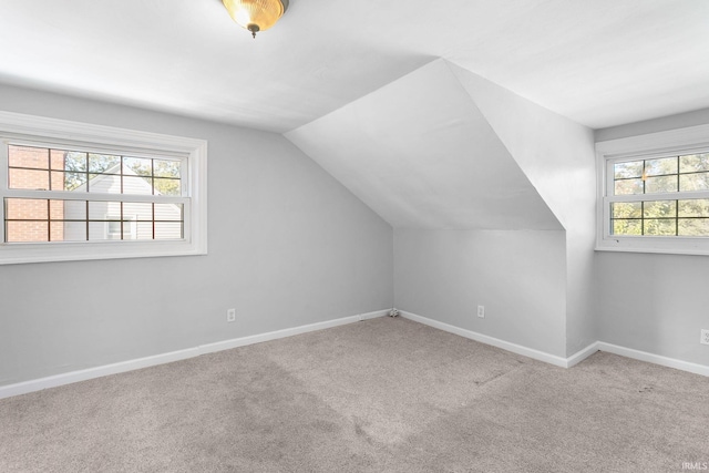 bonus room with lofted ceiling and light colored carpet