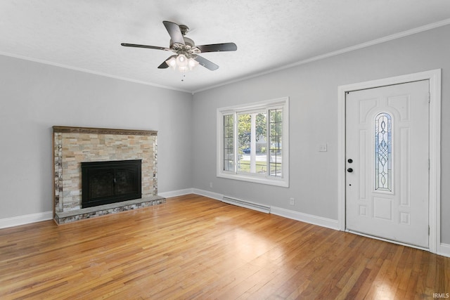 unfurnished living room featuring a baseboard heating unit, a stone fireplace, ceiling fan, crown molding, and hardwood / wood-style flooring