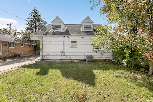 rear view of house featuring central air condition unit and a lawn