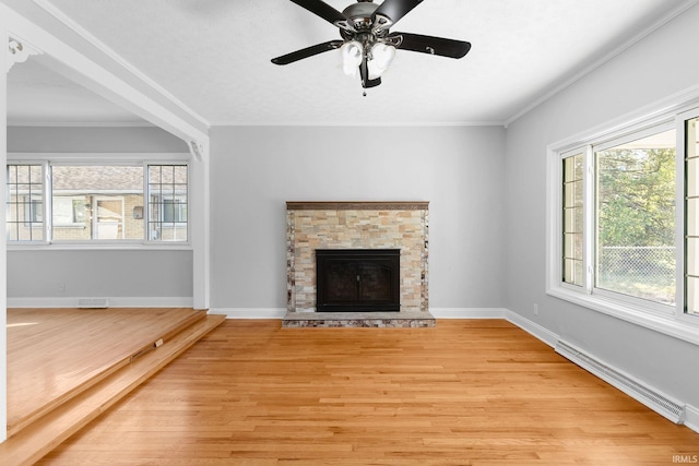 unfurnished living room with a stone fireplace, ornamental molding, a baseboard radiator, and light wood-type flooring