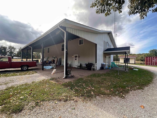 view of side of home with a patio, a lawn, and a carport