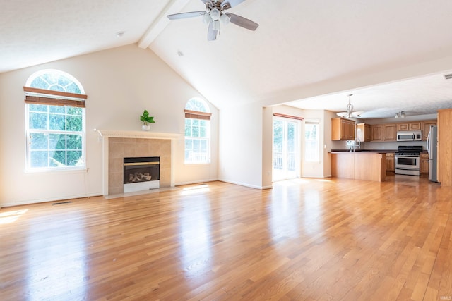 unfurnished living room featuring plenty of natural light, beamed ceiling, and light wood-type flooring