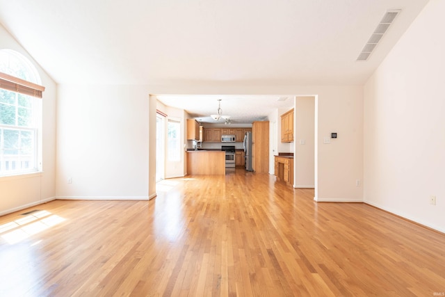unfurnished living room with a chandelier, baseboards, visible vents, and light wood-style floors
