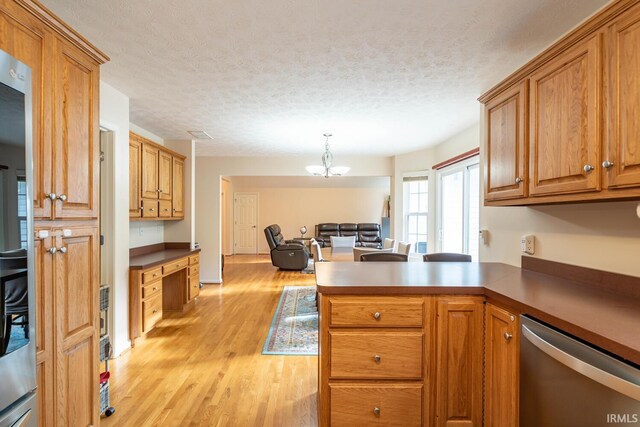 kitchen featuring dishwasher, light hardwood / wood-style flooring, hanging light fixtures, kitchen peninsula, and a textured ceiling