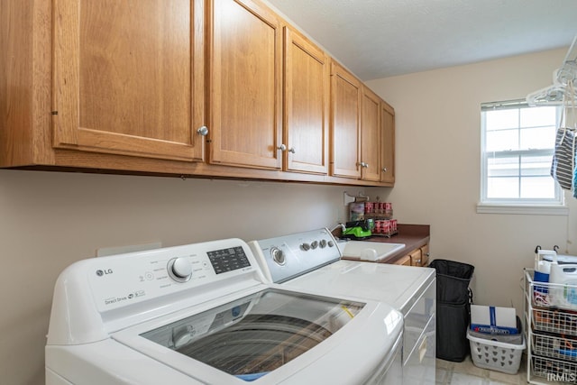 laundry room with a textured ceiling, cabinets, and washing machine and clothes dryer