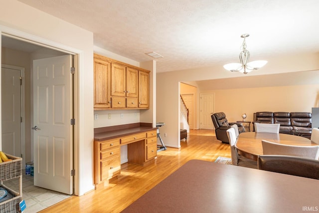 dining room featuring light wood-style floors, built in study area, and stairway