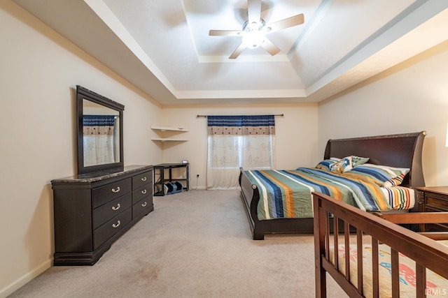 bedroom featuring ceiling fan, light carpet, and a tray ceiling