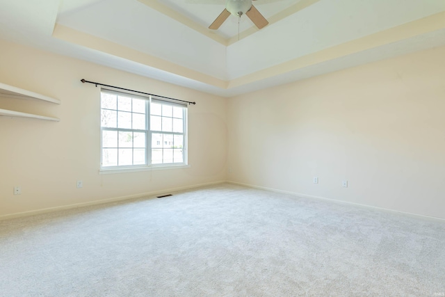 empty room featuring baseboards, a ceiling fan, a tray ceiling, and carpet flooring