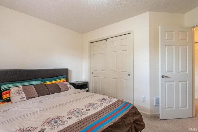 carpeted bedroom featuring a closet and a textured ceiling