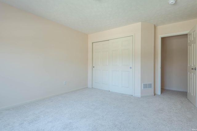 unfurnished bedroom with carpet floors, baseboards, visible vents, and a closet