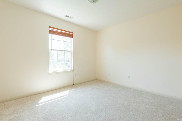 spare room with carpet floors, baseboards, and visible vents
