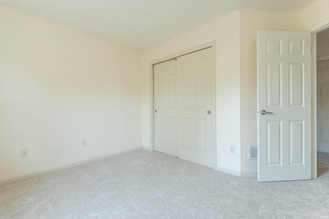unfurnished bedroom featuring carpet floors, baseboards, a closet, and visible vents