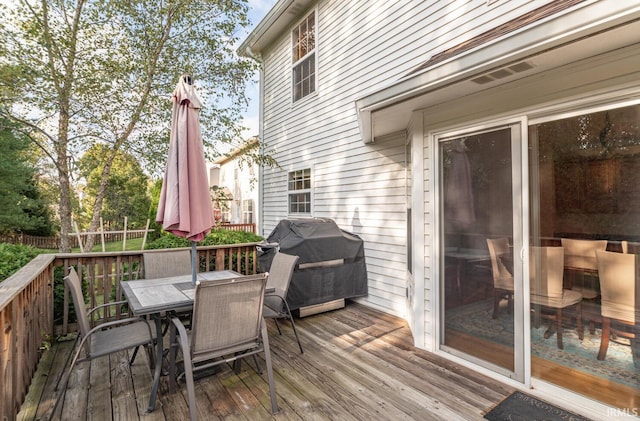 wooden terrace with outdoor dining area, fence, and area for grilling