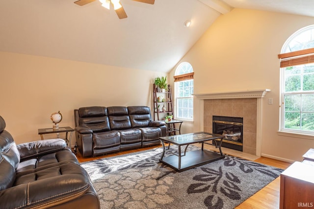 living room with ceiling fan, hardwood / wood-style flooring, a tile fireplace, and plenty of natural light