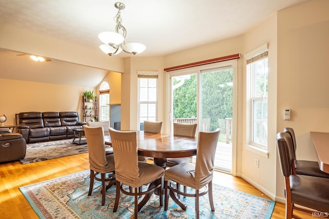 dining room featuring an inviting chandelier, light hardwood / wood-style flooring, and vaulted ceiling