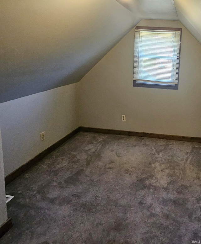 bonus room featuring dark colored carpet and lofted ceiling