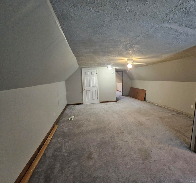 bonus room featuring carpet flooring, vaulted ceiling, and a textured ceiling