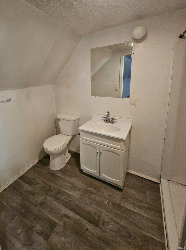 bathroom featuring vaulted ceiling, wood-type flooring, vanity, toilet, and a textured ceiling