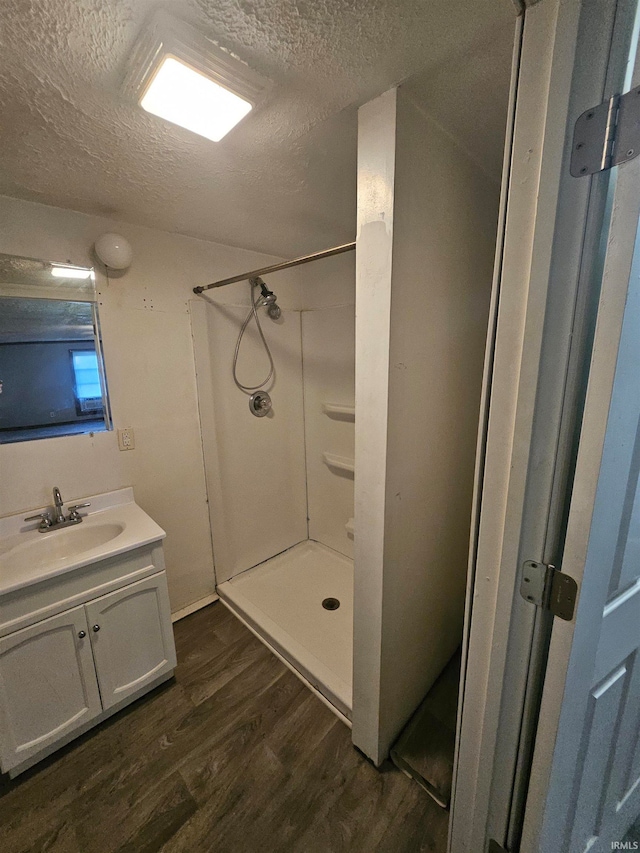 bathroom featuring vanity, hardwood / wood-style floors, a textured ceiling, and a shower