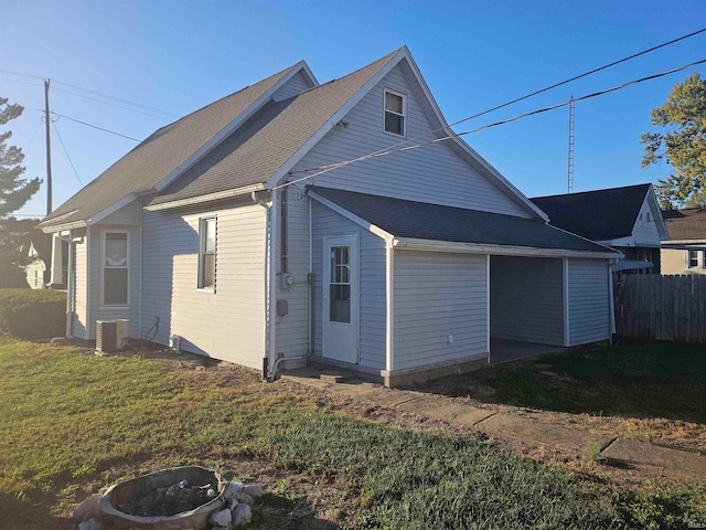 view of side of property with an outdoor fire pit, cooling unit, and a lawn