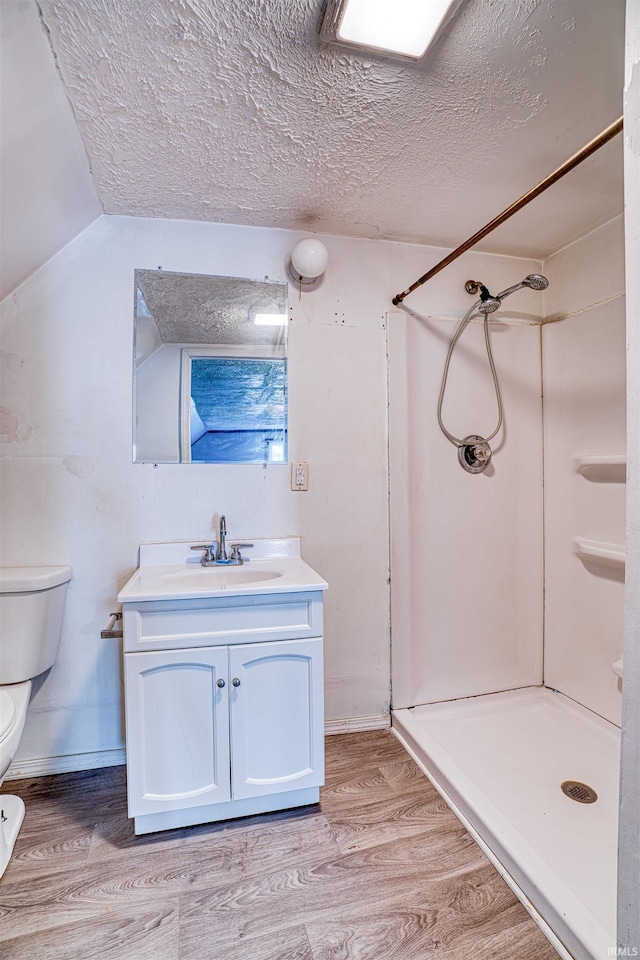 bathroom featuring vanity, wood-type flooring, a textured ceiling, toilet, and walk in shower