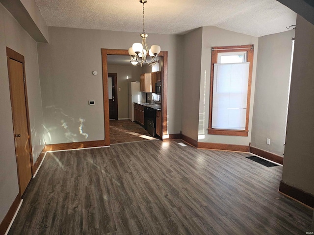 unfurnished dining area featuring an inviting chandelier, lofted ceiling, dark hardwood / wood-style floors, and a textured ceiling