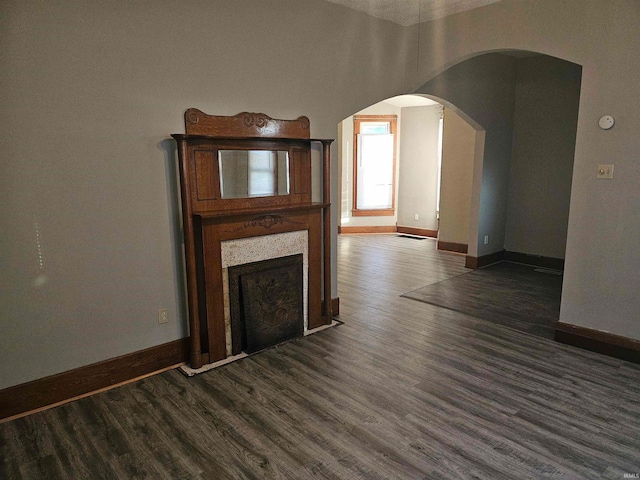 unfurnished living room featuring dark wood-type flooring and a textured ceiling