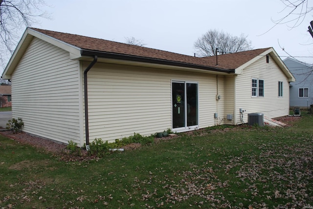 rear view of house with central AC and a lawn