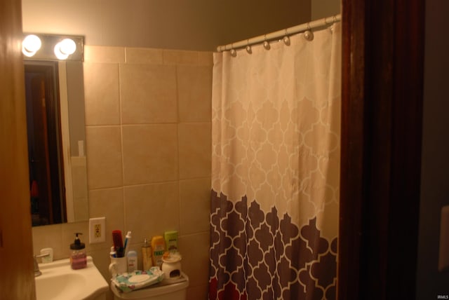 bathroom with tile walls, sink, a shower with shower curtain, and toilet