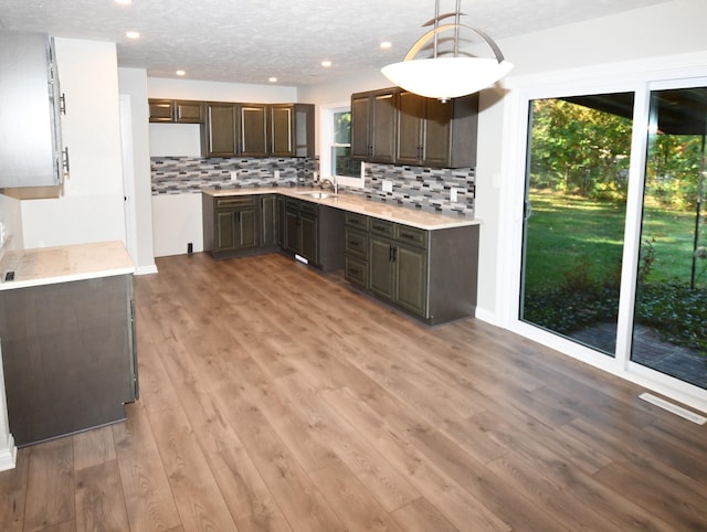 kitchen with hardwood / wood-style floors, a textured ceiling, plenty of natural light, pendant lighting, and sink