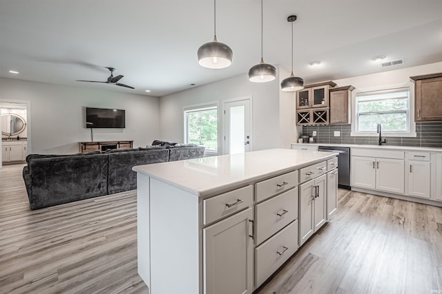 kitchen featuring a healthy amount of sunlight, dishwasher, a center island, and white cabinetry