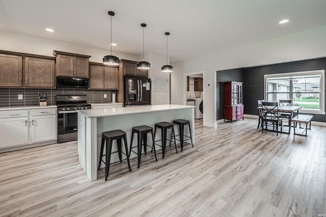 kitchen with light hardwood / wood-style flooring, black appliances, decorative light fixtures, and a kitchen island