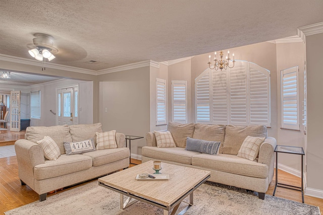 living room featuring ornamental molding, a textured ceiling, ceiling fan with notable chandelier, and light hardwood / wood-style floors