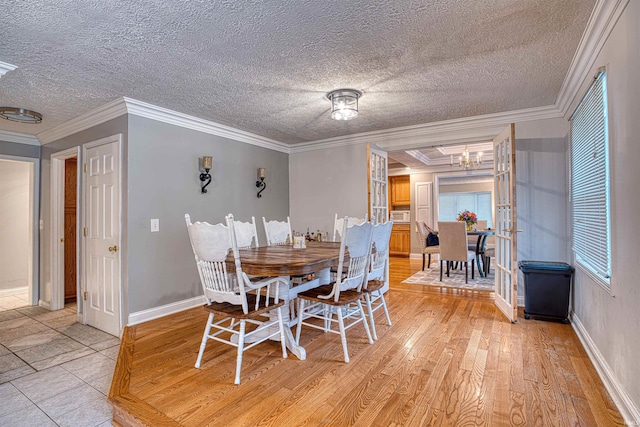 dining room with light hardwood / wood-style floors, ornamental molding, and a textured ceiling