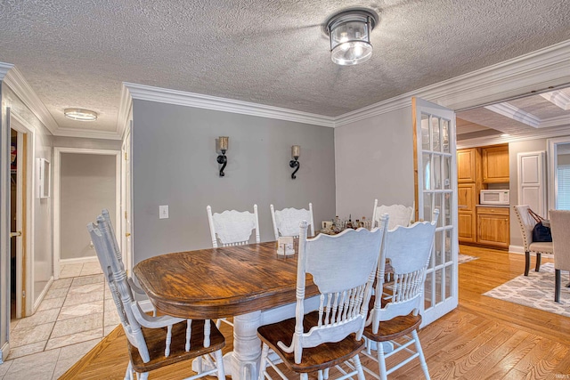 dining room featuring beam ceiling, crown molding, light hardwood / wood-style flooring, and a textured ceiling