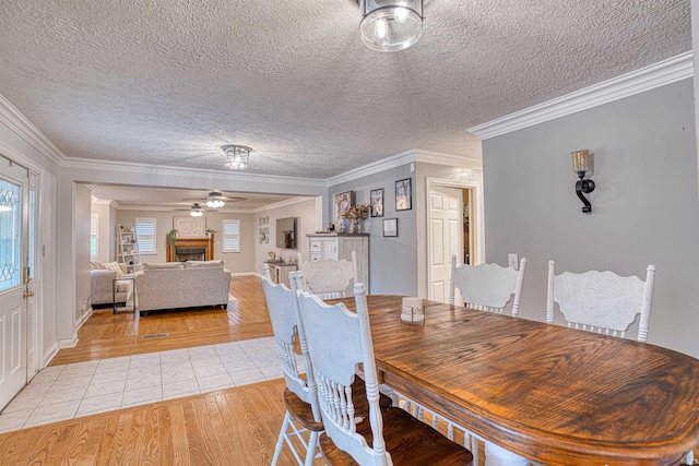 dining area with ornamental molding, a textured ceiling, light wood-type flooring, and ceiling fan