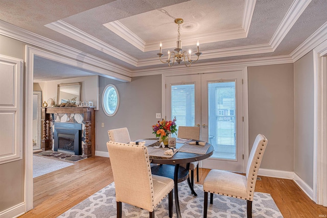 dining space with ornamental molding, a tray ceiling, and light wood-type flooring