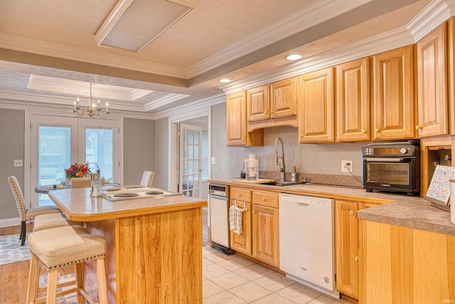 kitchen featuring sink, dishwasher, a raised ceiling, ornamental molding, and a kitchen island with sink