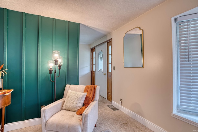 living area with a textured ceiling and light colored carpet