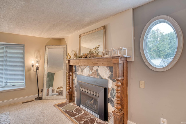 living room with a stone fireplace, a textured ceiling, and carpet floors