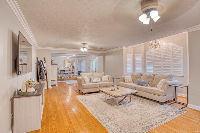 living room featuring hardwood / wood-style flooring, a textured ceiling, ornamental molding, and ceiling fan with notable chandelier